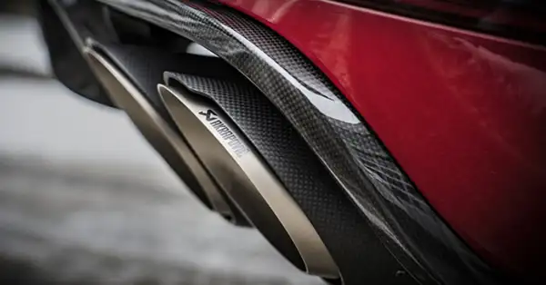 Rear side view of an Akrapovic exhaust installed on a Red Porsche Macan.